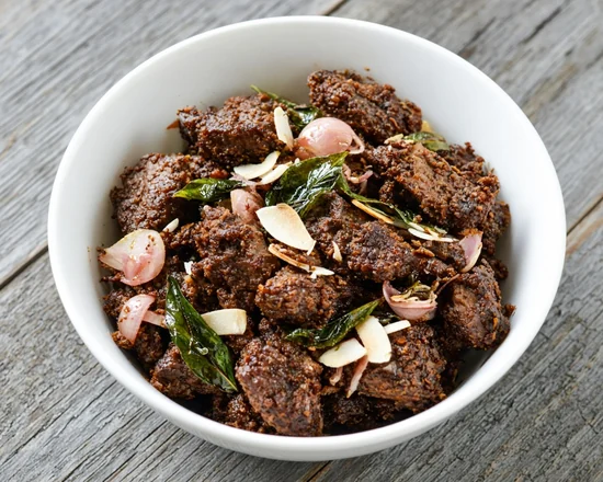 Beef Varattiyath: dry-roasted Kerala beef with curry leaves and shallots in a white bowl